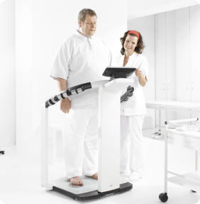 Profesional de la salud usando analizador de composición corporal Seca con paciente.